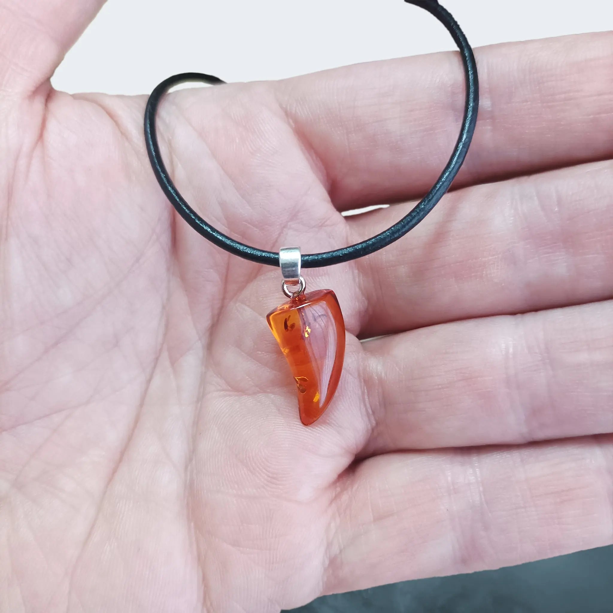 Hand-Cut & Polished Amber Pendant, Shaped into a Wolf's / Dragon's Tooth with Sterling Silver Hanger on Leather Cord, on Hand