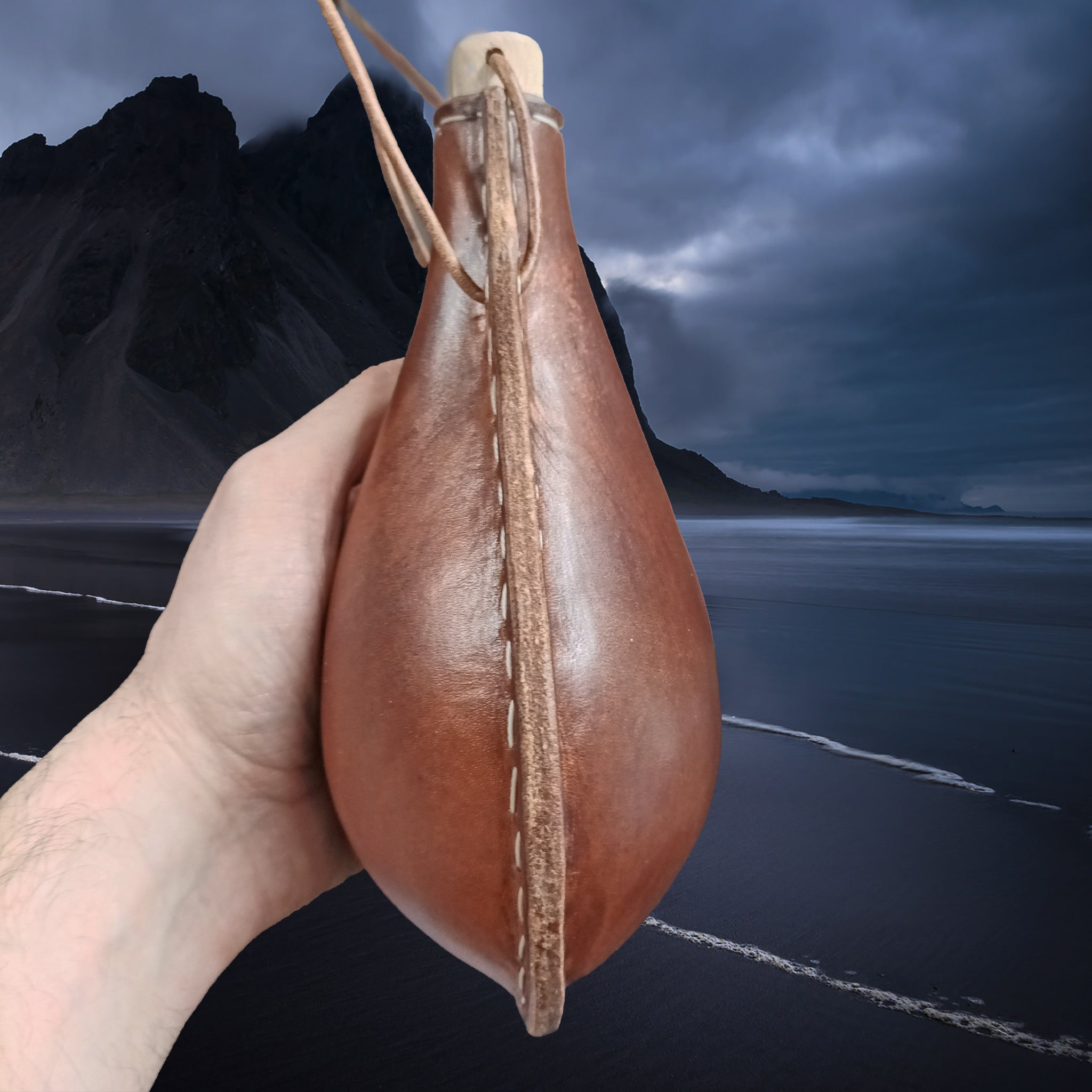 Handmade Thick Boiled Leather Water Bottle with Wood Stopper & Leather Thong Strap in Hand - Side View