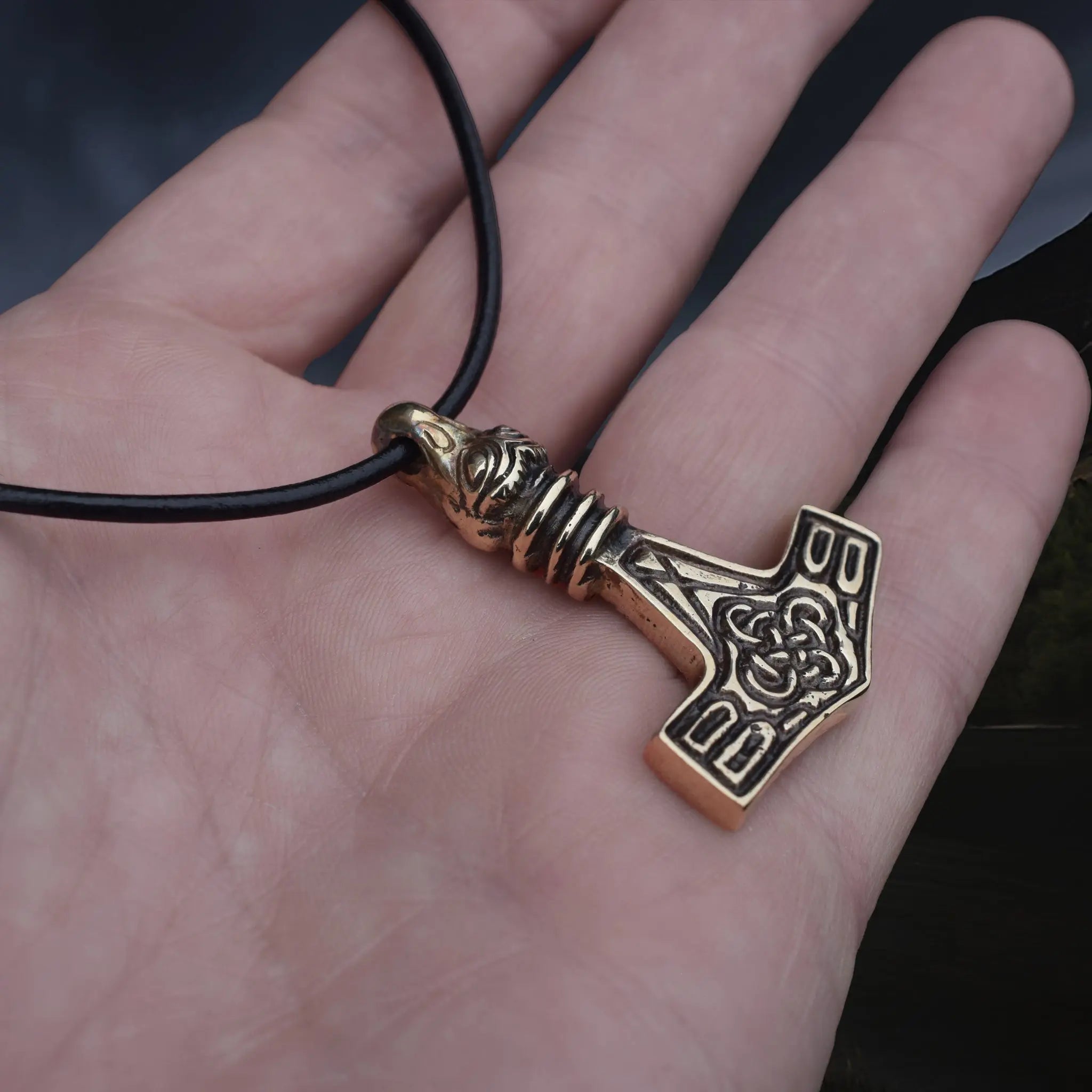 Replica Bronze Viking Age Thor's Hammer Pendant from Sweden with Raven Head on Leather Cord, on Hand - Angle View
