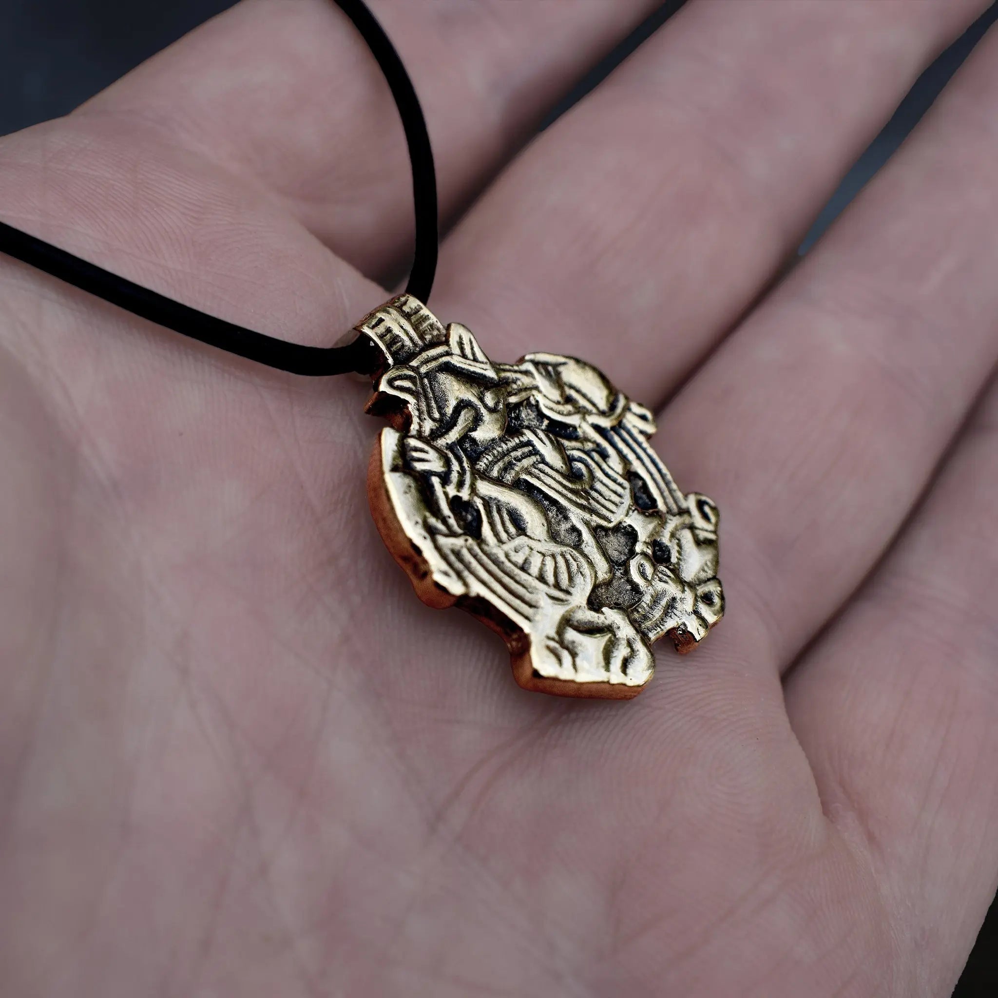 Solid Bronze Replica Viking Gripping Beats Pendant from 10th century Sweden on Leather Cord, on Hand - Side Angle View