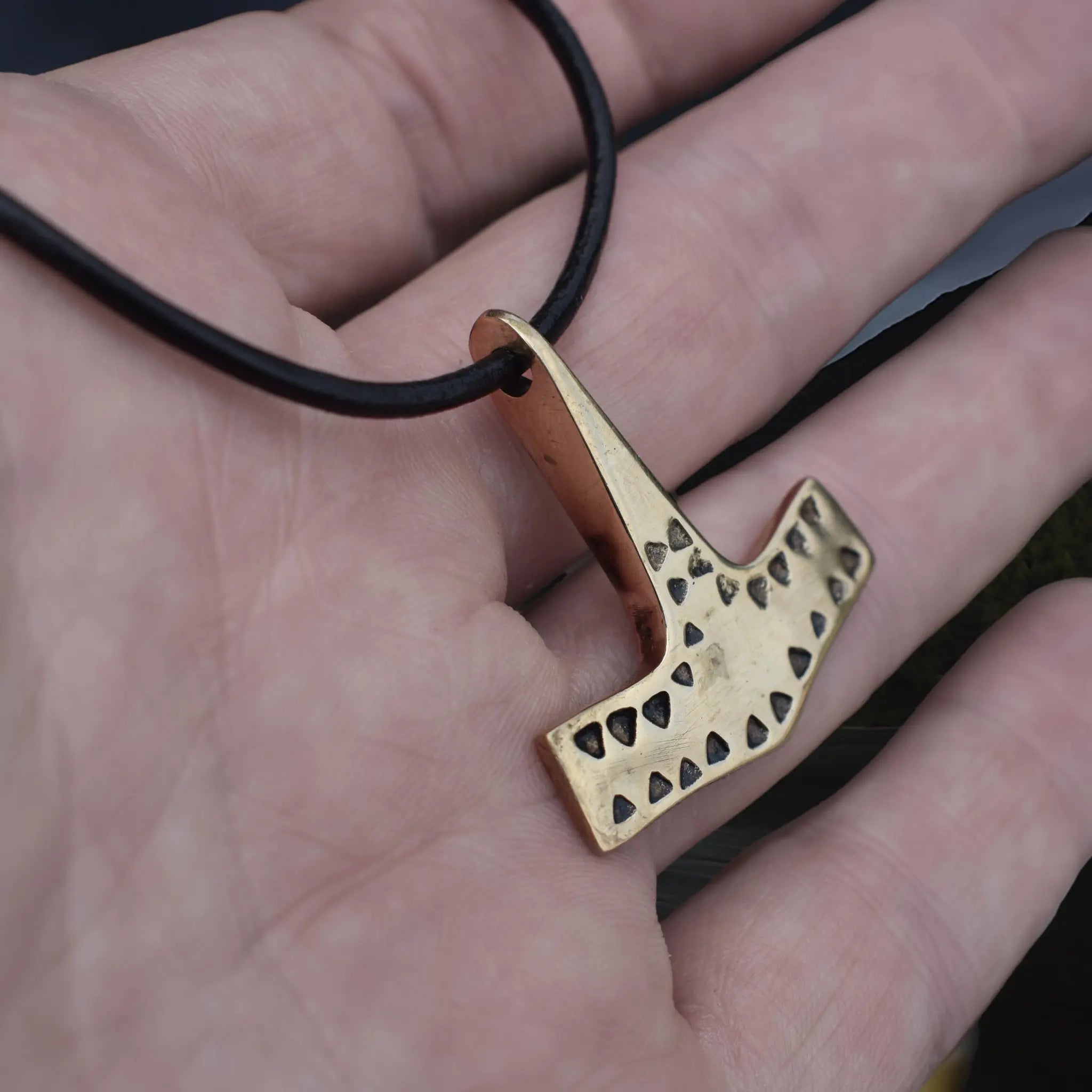 Bronze Viking Thor's Hammer Pendant Replica from 10th Century Denmark with Triangle Patterns on Leather Cord, on Hand- Side Angle View