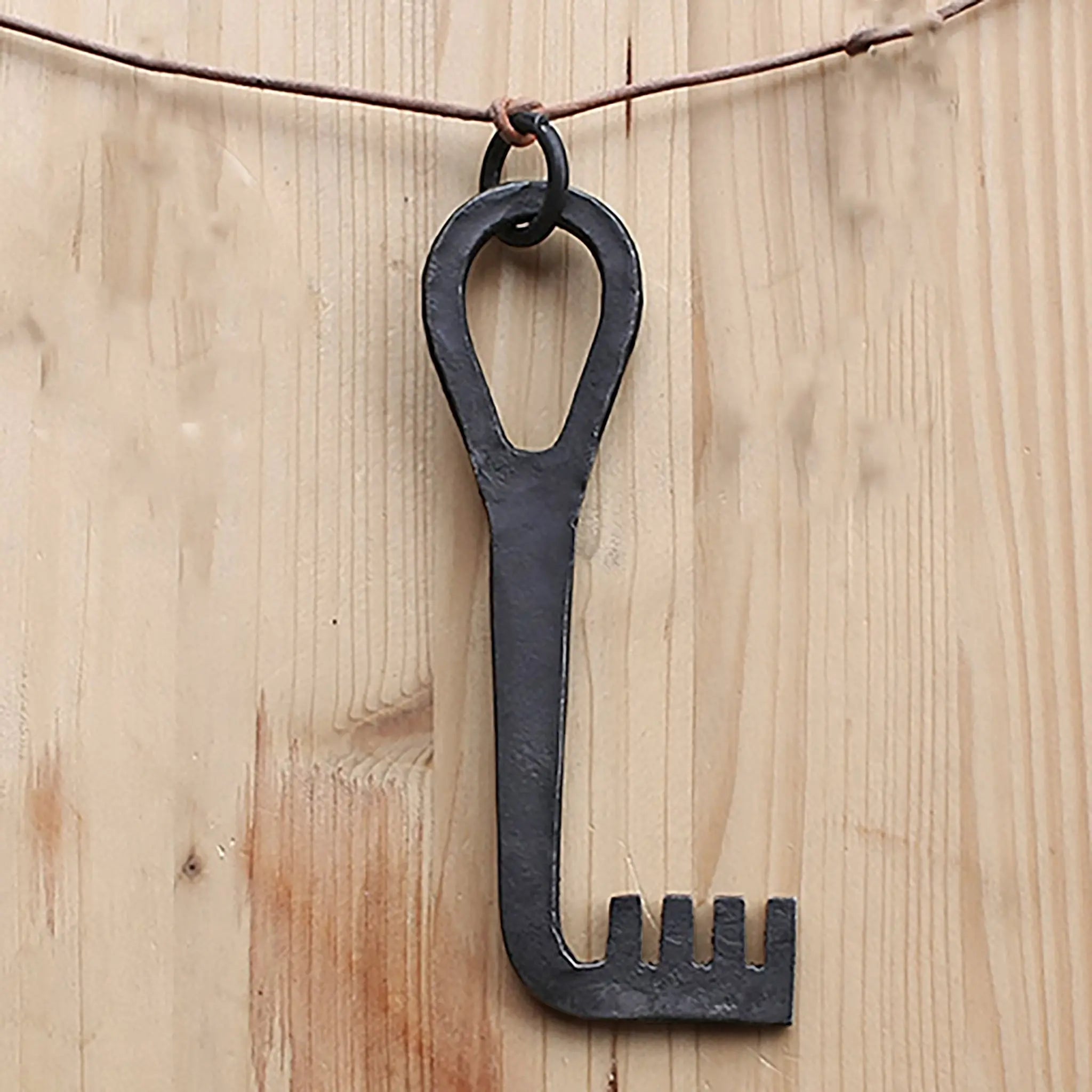Large, Hand-Forged Iron Viking Key Replica with Iron Suspension Ring on Leather Cord - On Wood Background
