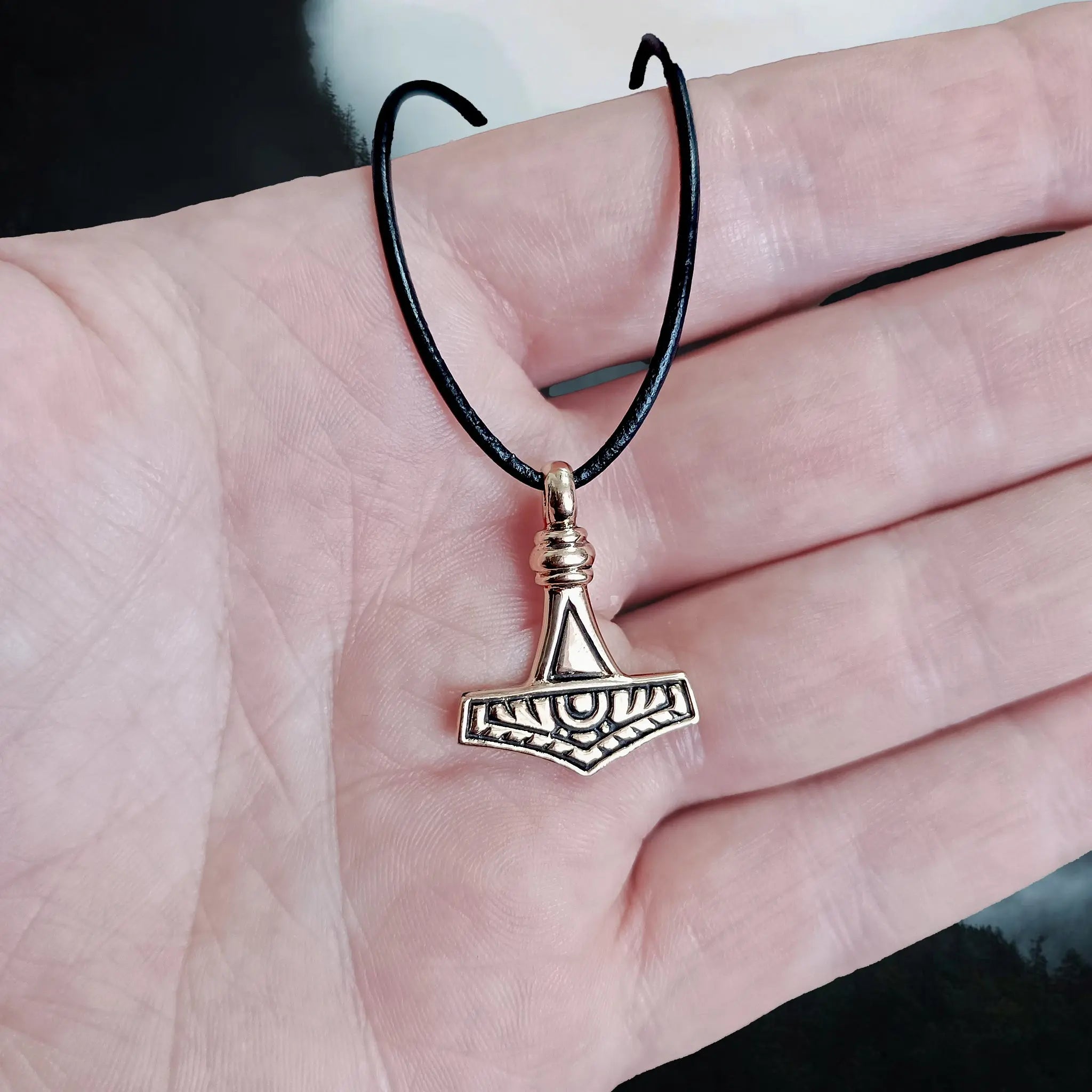 Small Replica Bronze Viking Thor's Hammer Pendant from the Island of Gotland, Sweden on Leather Thong on Hand - Front View