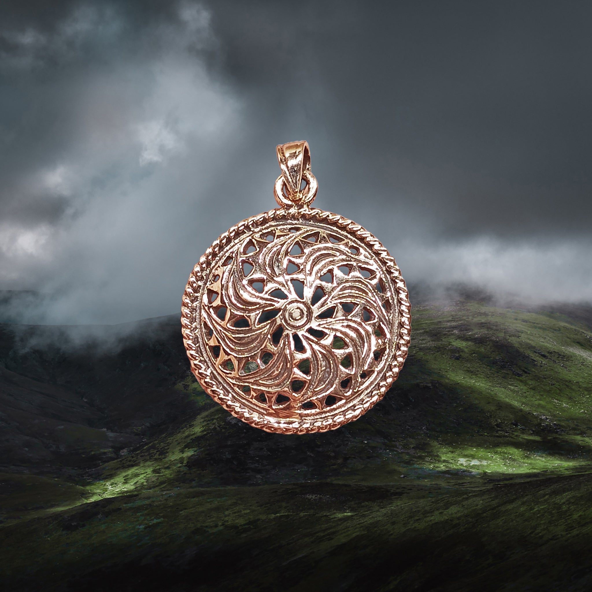 Bronze Sun Wheel Pendant on Cloudy Hills Background