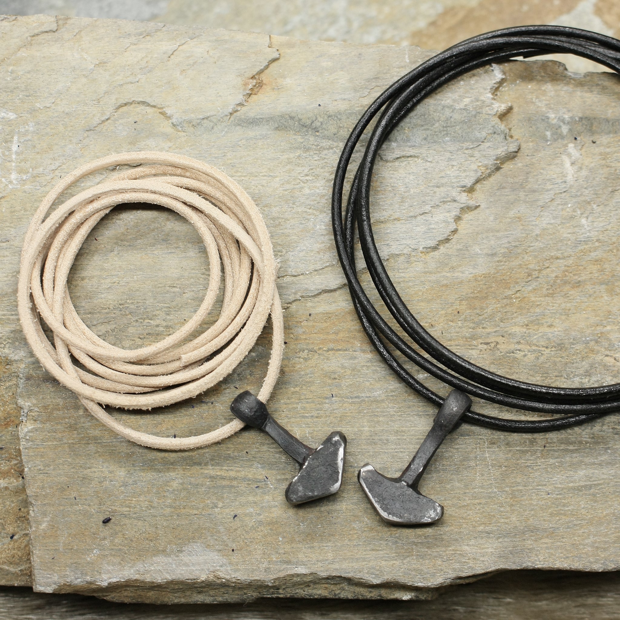 Hand Forged Replica Iron Thors Hammer Pendants on Thongs on Rock