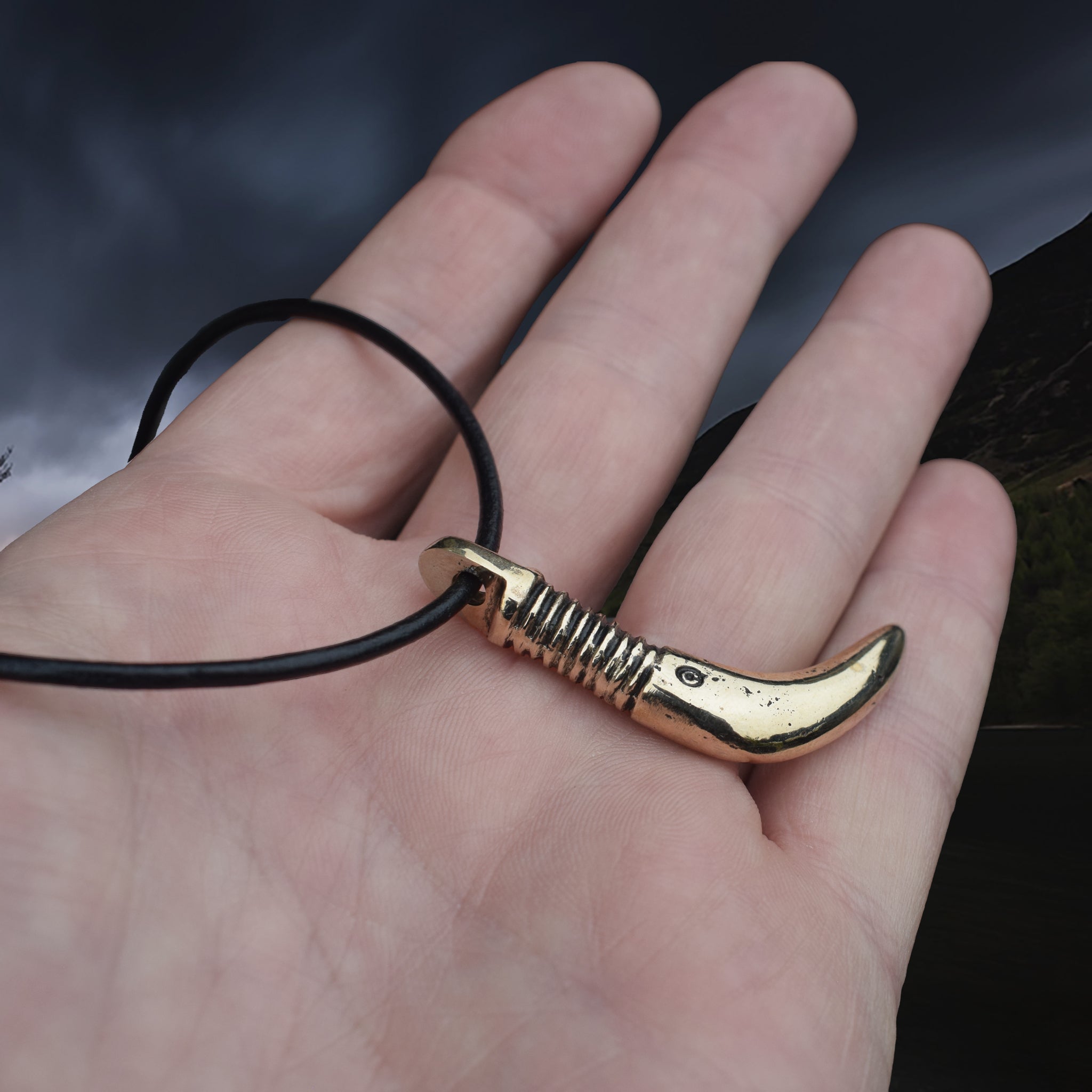 Solid Bronze Replica Viking Bear Tooth Pendant from 9th to 11th century Finland on Leather Cord, on Hand - Side Angle View
