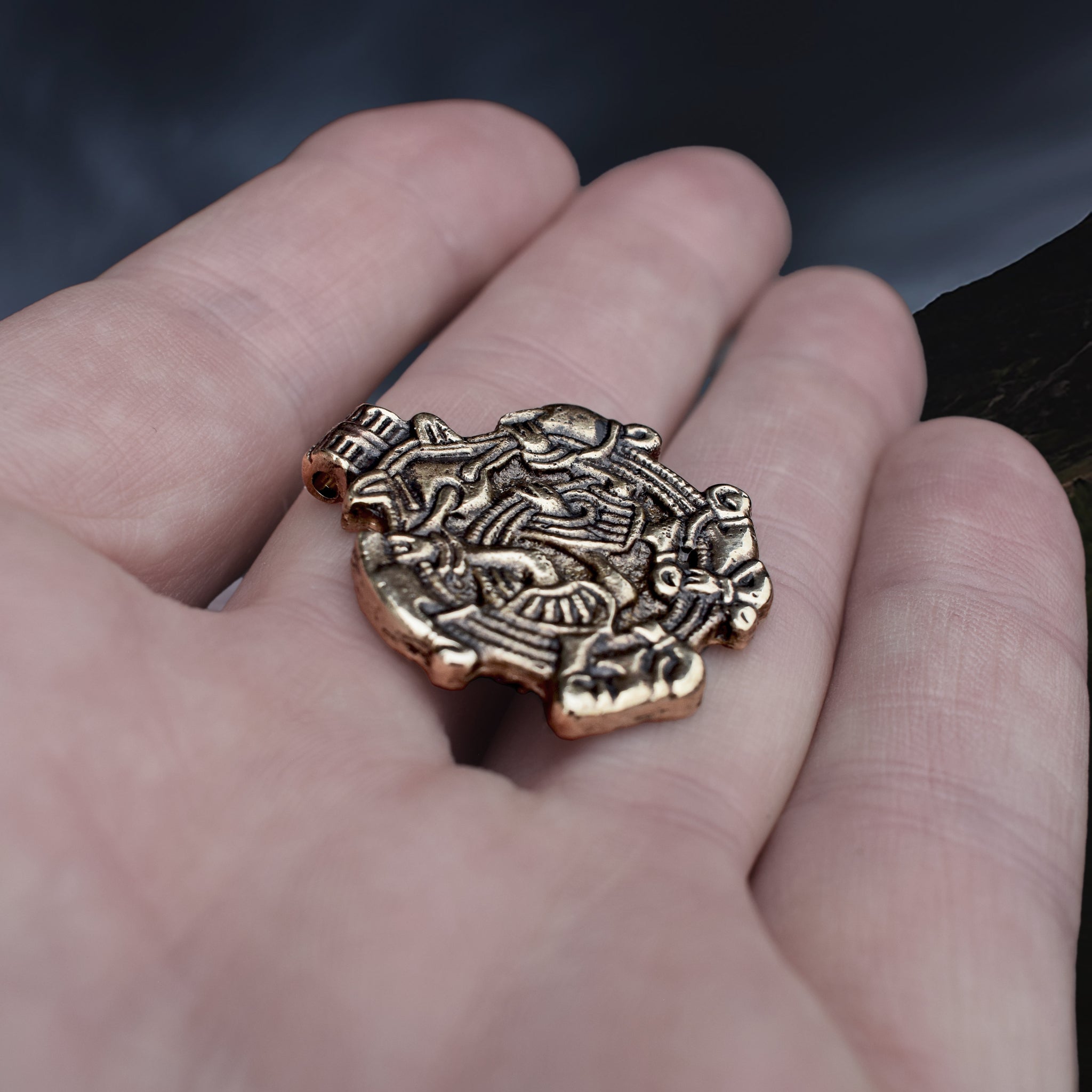 Solid Bronze Replica Viking Gripping Beats Pendant from&nbsp; 10th century Sweden on Hand - Side Angle View