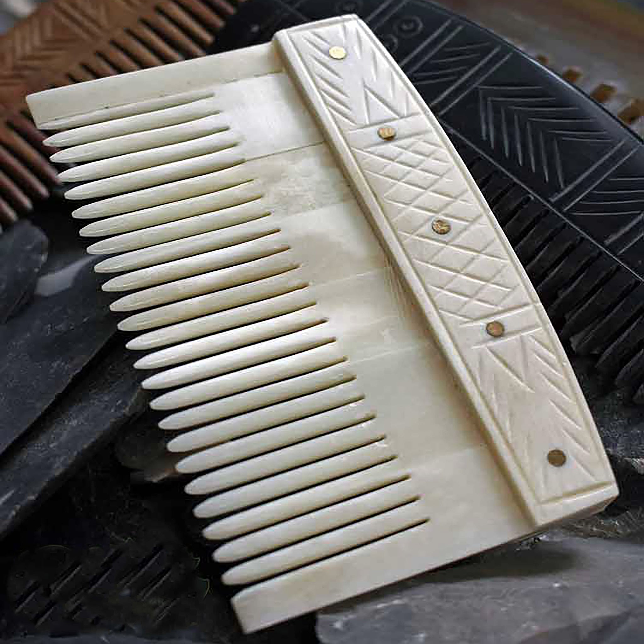 Decorated Bone Viking Comb with Rivets on top of other combs