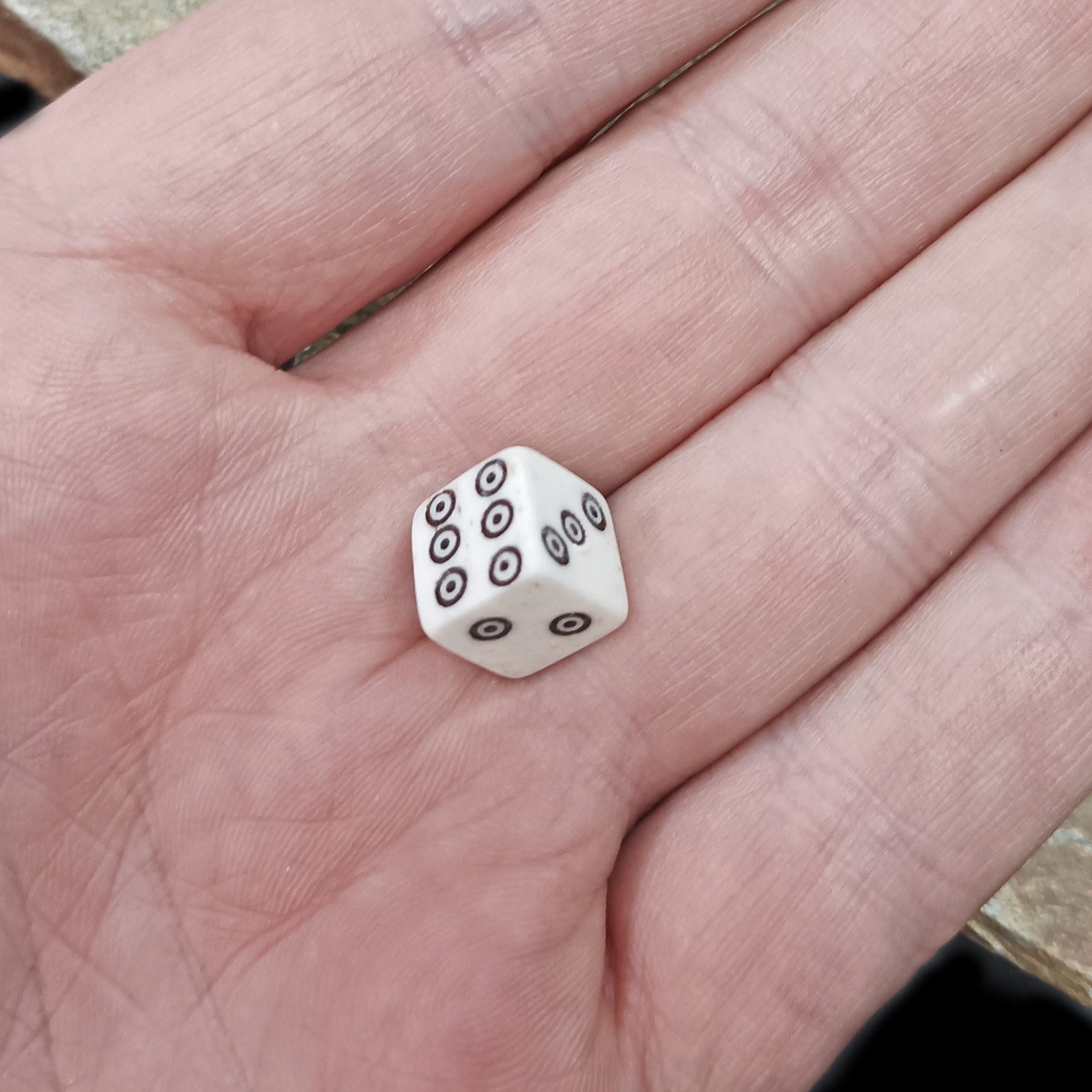 Small Natural Bone Replica Viking Die with Black Dot and Ring Incised Spots in Hand