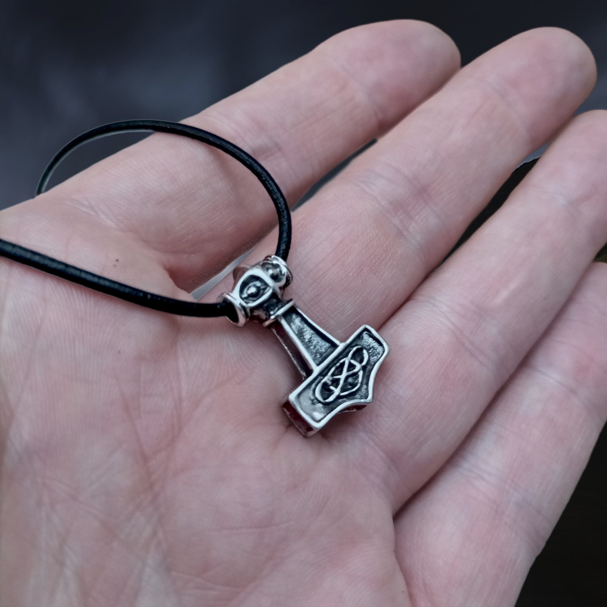 Small Silver Thunder Thors Hammer Viking Pendant on Leather Thong on Hand - Angle View