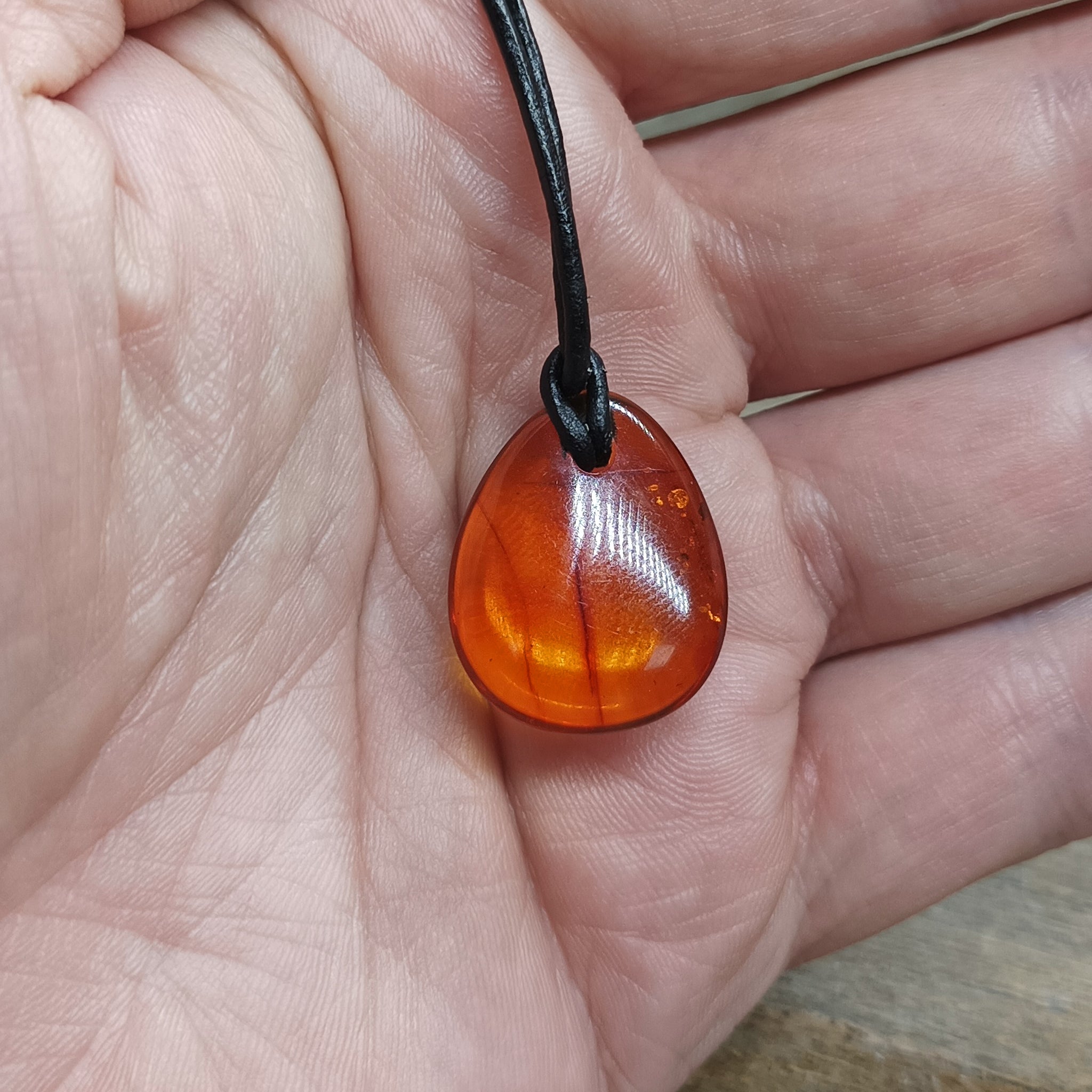 Amber Amulet Pendant on Hand with Leather Thong