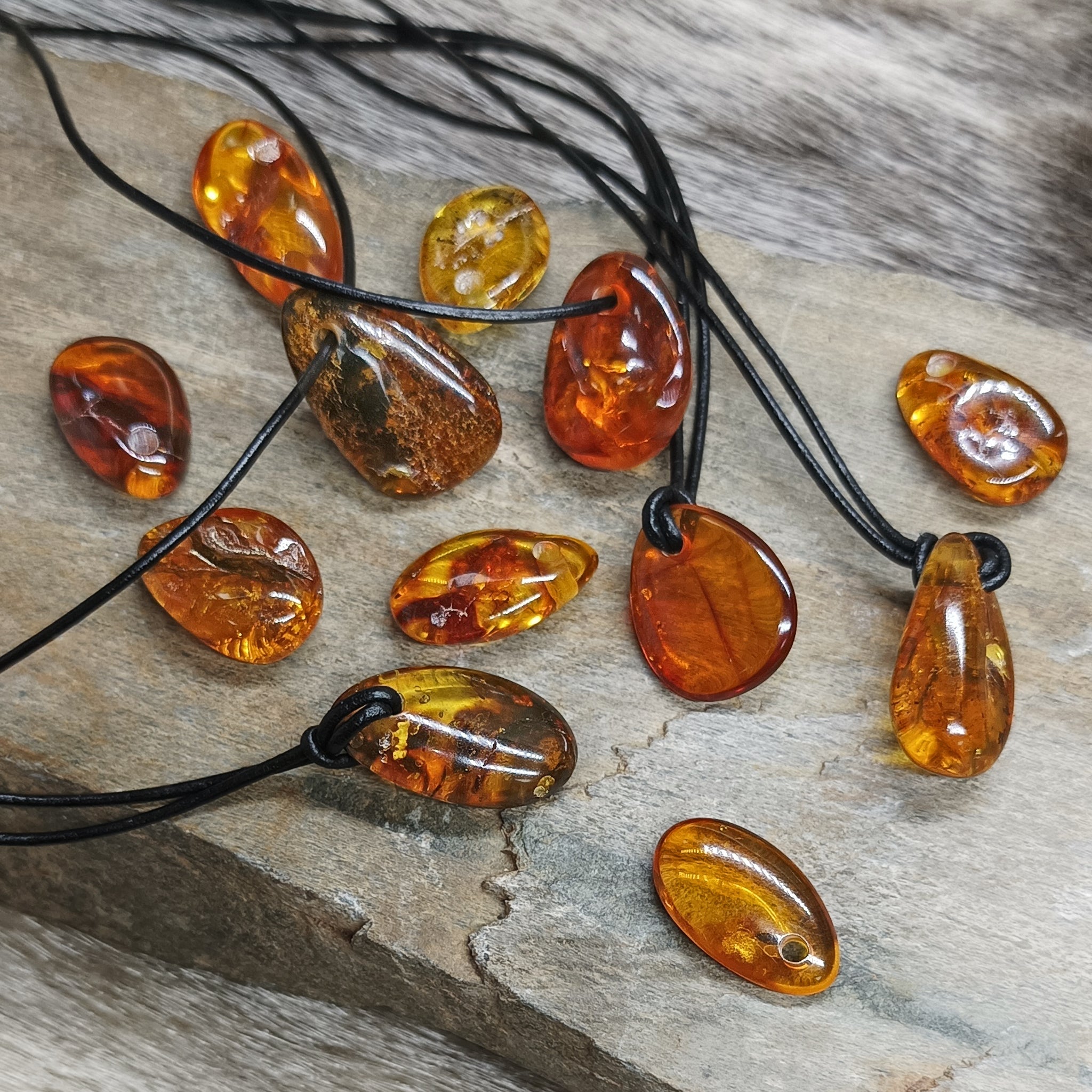 Amber Amulet Pendants on Rock with and without Leather Thongs